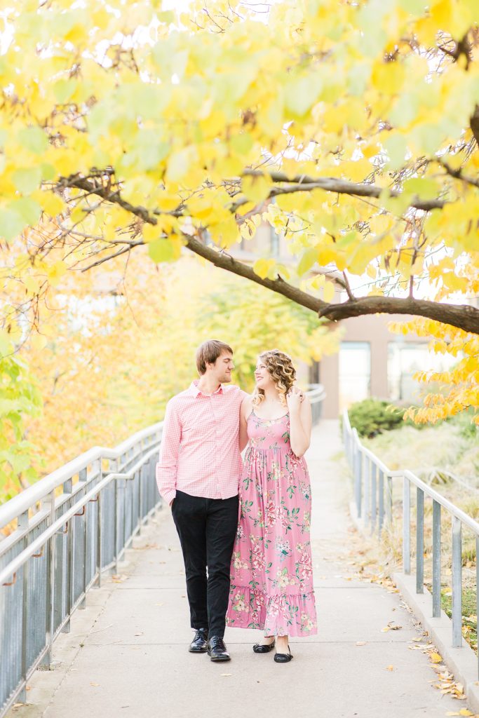 couple walking on tree-lined path during an autumn engagement session