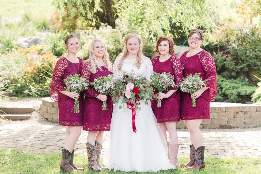 bride standing with bridesmaids wearing cranberry lace dresses