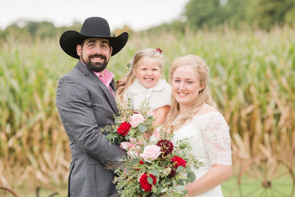 bride and groom smiling with flower girl