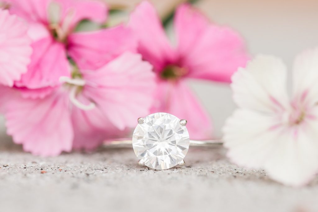 diamond engagement ring next to pink flower